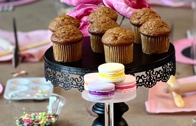 Black cake stand with muffins and a tier of pastel macarons