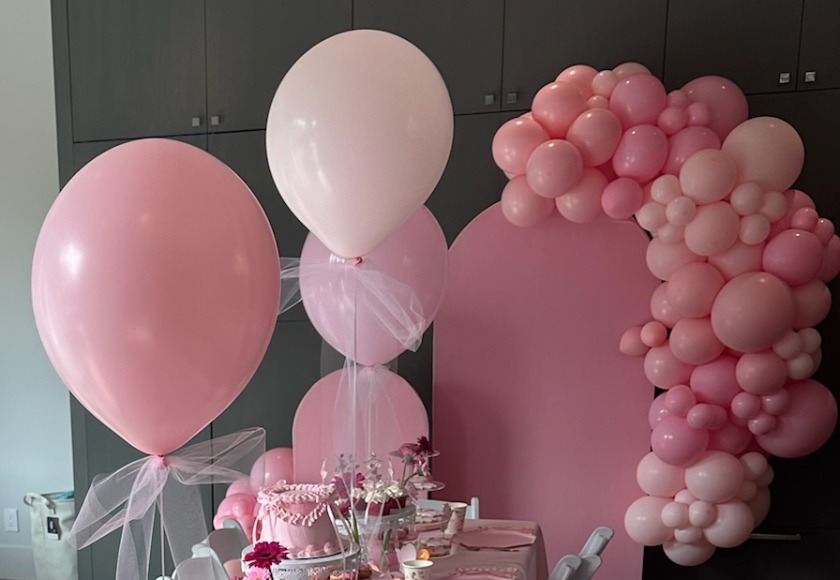 Pink balloon cluster and balloon arch against a soft pink backdrop